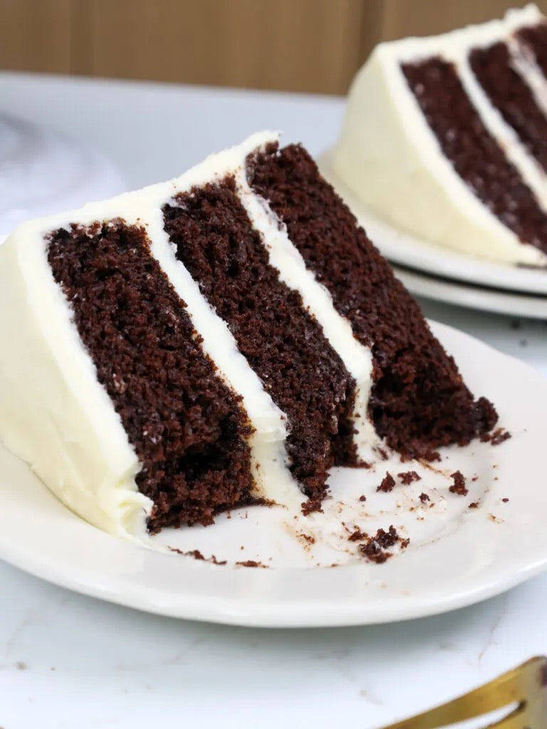 a slice of triple layer chocolate cake with vanilla buttercream icing